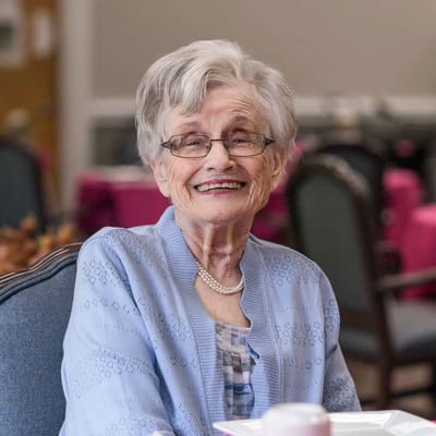 Elderly resident smiling in a dining area