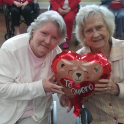 Two residents holding a heart-shaped balloon in a common area