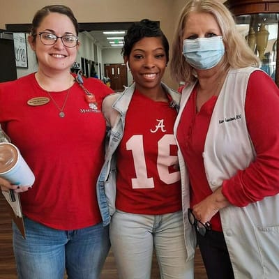 Three staff members smiling together indoors