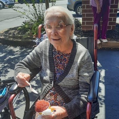 Resident enjoying a treat outdoors in a wheelchair