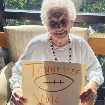 Senior resident holding a handmade sign supporting a football team