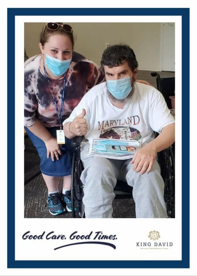 Resident and staff member posing with a thumbs-up