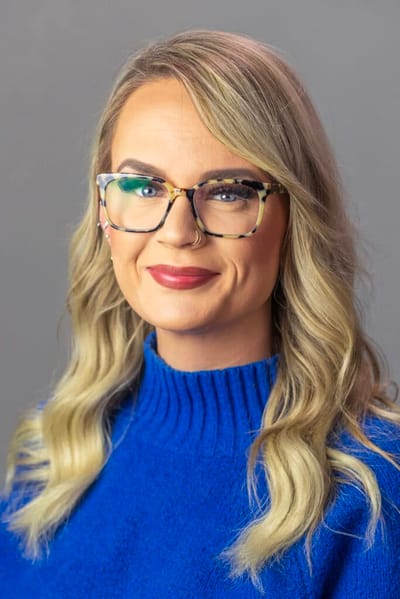 Smiling woman with glasses in a blue sweater