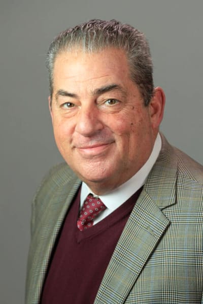 A man in a professional suit smiling at the camera