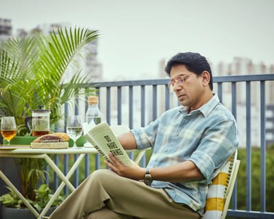 A resident enjoying a book on a balcony with refreshments
