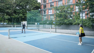 Residents playing tennis in a sunny outdoor court