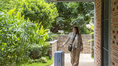 A resident arriving with a suitcase in a green outdoor area