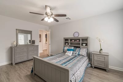 A well-furnished private resident room with a bed and dresser