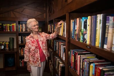 Resident browsing books in a cozy library setting