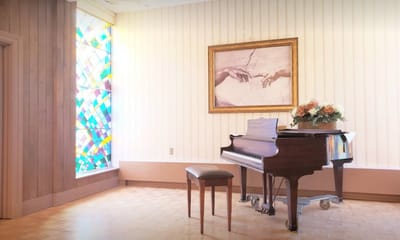 Interior view of a room featuring a piano and stained glass window