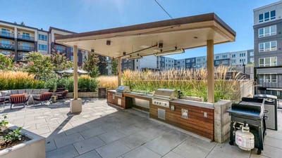 Outdoor grilling area with seating and landscaped surroundings