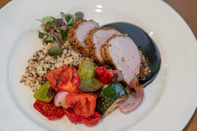 Plated meal of sliced pork with vegetables and quinoa