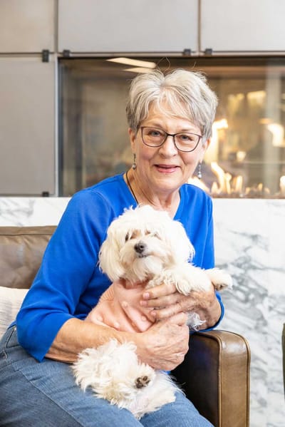 Senior resident smiling with a small dog in a cozy living area