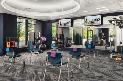 Bright fitness center with exercise equipment and chairs