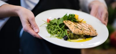 A beautifully plated salmon dish served by a staff member