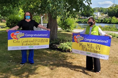 Two staff members celebrating with banners in the garden