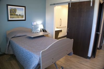 Private resident room with a hospital bed and bedside table
