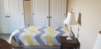A cozy bedroom with a colorful quilt and lamp