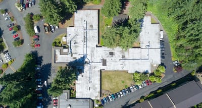 Aerial view of a facility surrounded by trees and parking