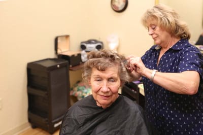 A beautician styling a resident's hair in a salon