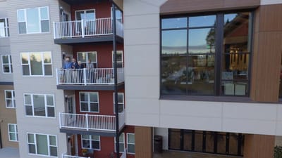 Residents on a balcony with a view of the facility