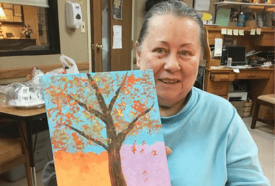 Resident showcasing a painting in a common area.