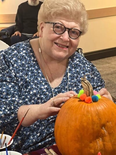 Resident decorating a pumpkin during an activity.