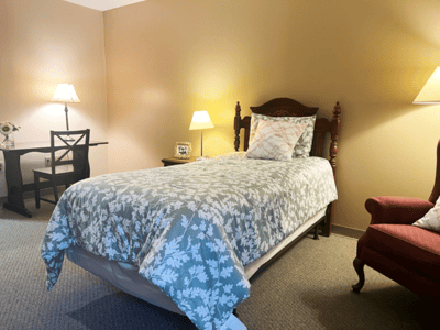 Cozy single bedroom with floral bedding and lamp.