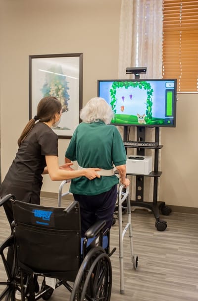 Staff assisting resident with interactive therapy game