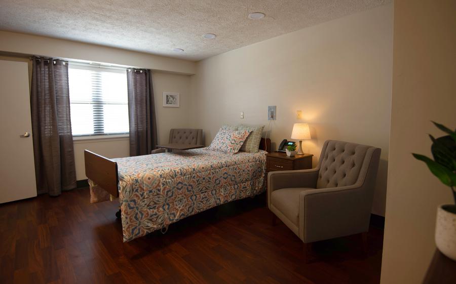 Well-furnished private resident room with a bed and armchair