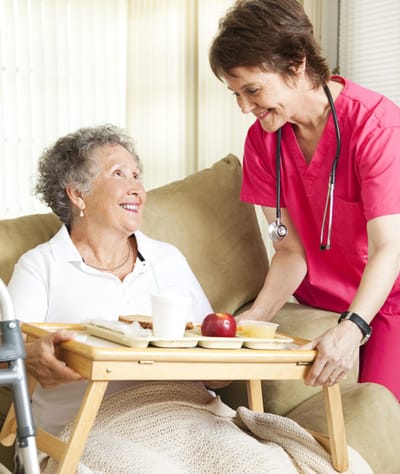 Healthcare worker serving a meal to a senior resident