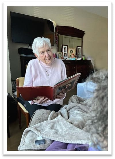 Elderly woman reading a book in a cozy setting.