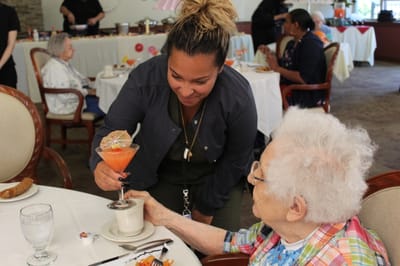 Staff serving food to a resident in the dining room.