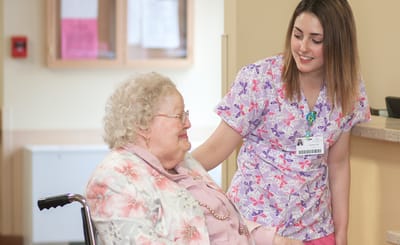 Resident smiling with staff in a nursing home