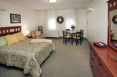 Cozy resident room with bed and dining area.