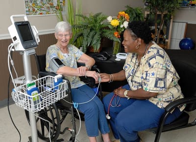 A nurse assists a resident with health monitoring.
