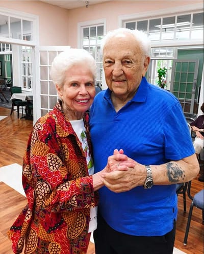 Two smiling residents dancing in a common area