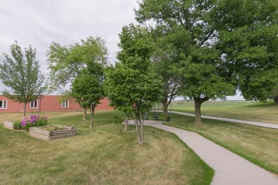 Pathway through gardens with trees at Colonial Manor