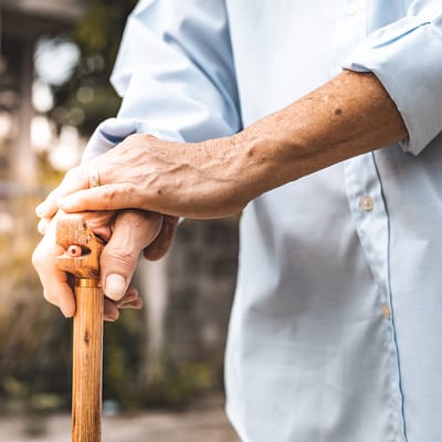 Close-up of an elderly person's hand on a wooden cane