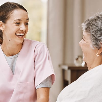 A caregiver laughing with a senior resident.