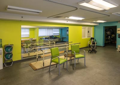 Rehabilitation room with equipment and green chairs
