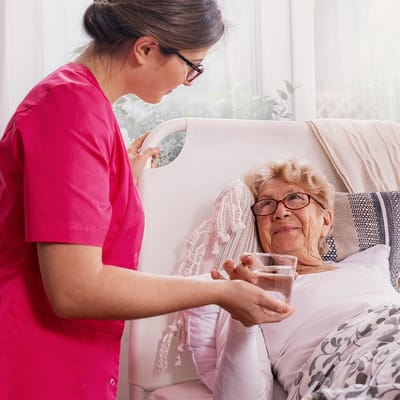Staff member assisting a resident with a glass of water