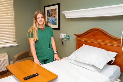 Staff member standing by a hospital bed in a patient room