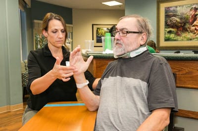 A staff member assisting a resident with rehabilitation exercises