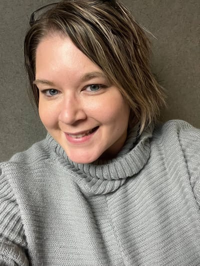 A woman smiling in a gray sweater