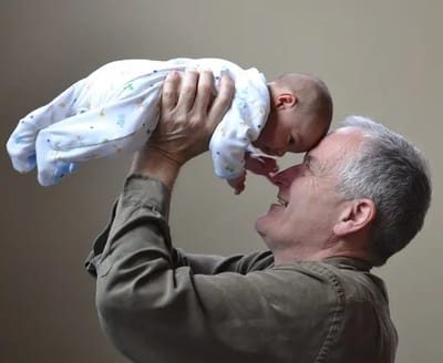 Senior man joyfully holding a baby