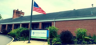 Fairlane Gardens at Reading, Nursing Home in Reading, PA — Fairlane Gardens at Reading entrance with American flag and landscaping