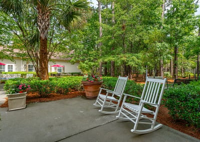 Outdoor seating area with rocking chairs and greenery