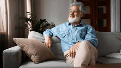 An older man sitting on a couch in a cozy interior