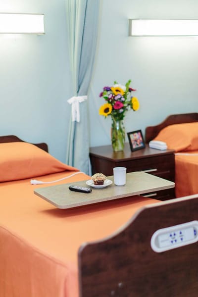 A cozy resident room with two beds and a flower vase